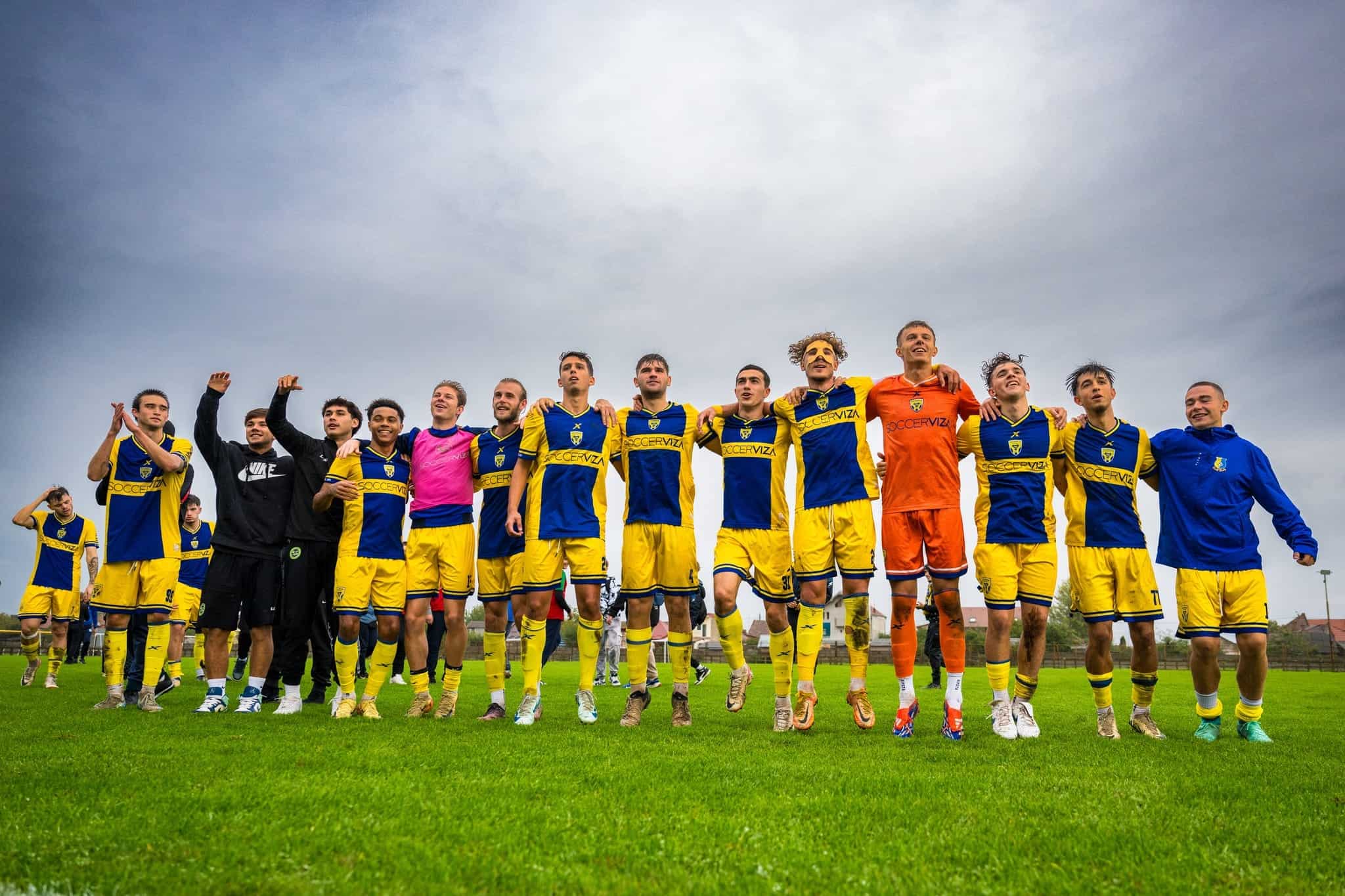 Jucători de fotbal pe teren, echipament galben și albastru, imagine de echipă sportivă.